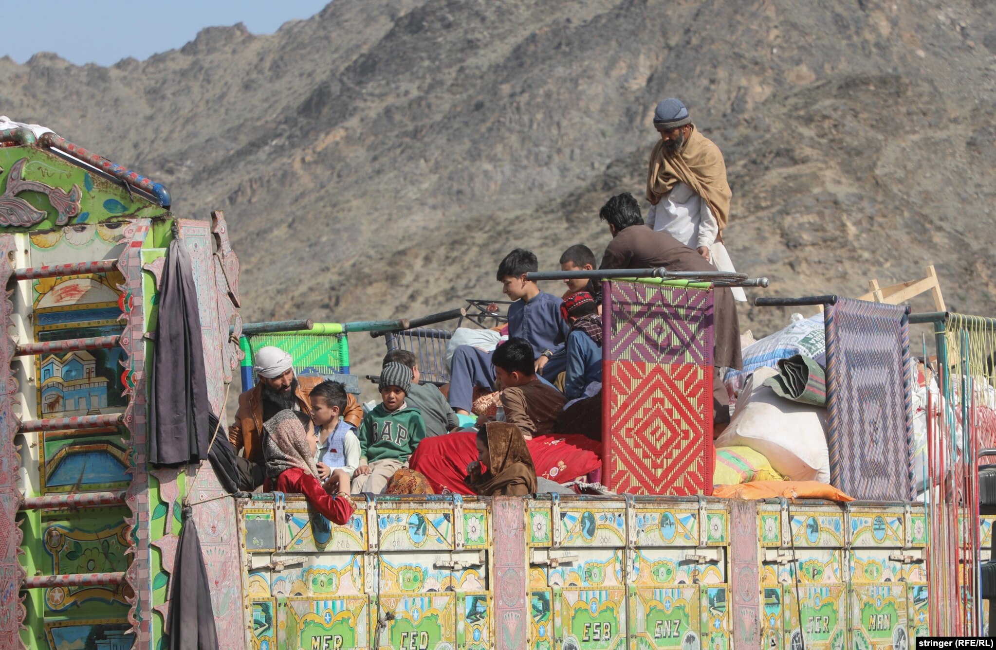 Afghan returnees ride atop a truck as they cross into Afghanistan. &nbsp;