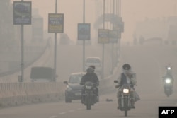 Navetiștii se deplasează pe un drum în condiții de smog dens în Amritsar, India, noiembrie 2023.