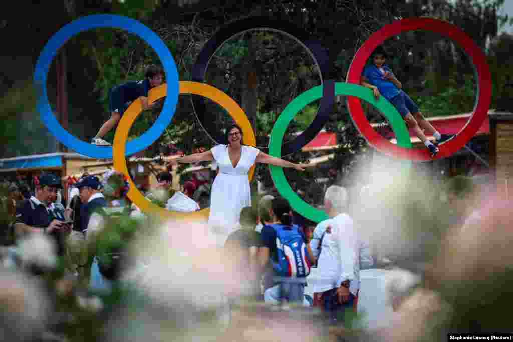 Një familje fotografohet në rrathët olimpikë në Portin e Versajës në Paris.