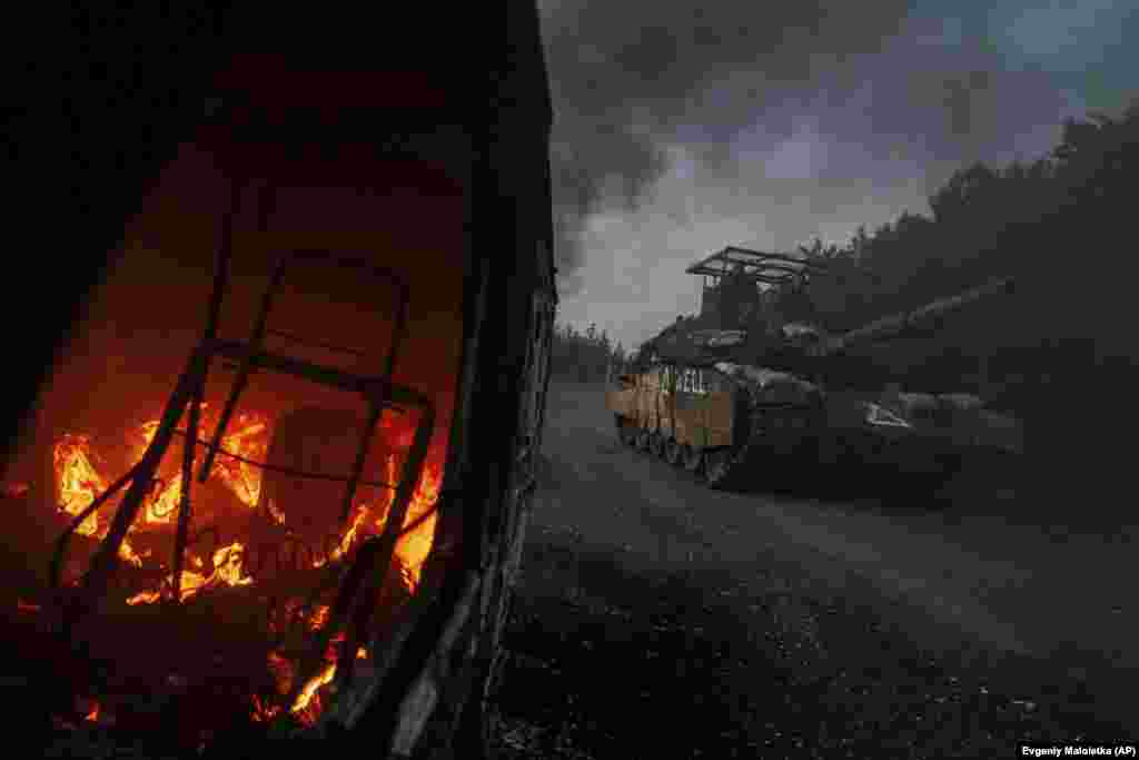 A Ukrainian tank passes by a burning car near the Russian-Ukrainian border in Ukraine&#39;s Sumy region.&nbsp;