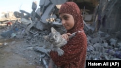 Palestinska djevojčica spašava svoju mačku iz ruševina uništenih zgrada nakon izraelskih zračnih napada u Rafi, južnom pojasu Gaze, srijeda, 18. oktobra 2023.
