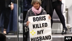 Жена държи плакат с надпис "Борис уби съпруга ми" по време на разпита на бившия британски премиер Борис Джонсън по разследването за предприетите от кабинета му мерки срещу разпространението на COVID-19, Западен Лондон, 7 декември 2023 г.