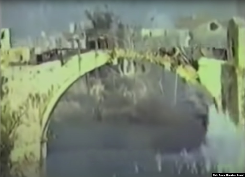Një kuadër i palëvizshëm nga një video tregon momentin kur ura filloi të shembet pasi u godit nga një predhë në mëngjesin e 9 nëntorit 1993. Në orën 10:16 të mëngjesit të 9 nëntorit, Eldin Palata, një 17-vjeçar banor i Mostarit po regjistronte video teksa ura u godit nga një predhë që bëri që struktura të rrëzohej në lumin Neretva.