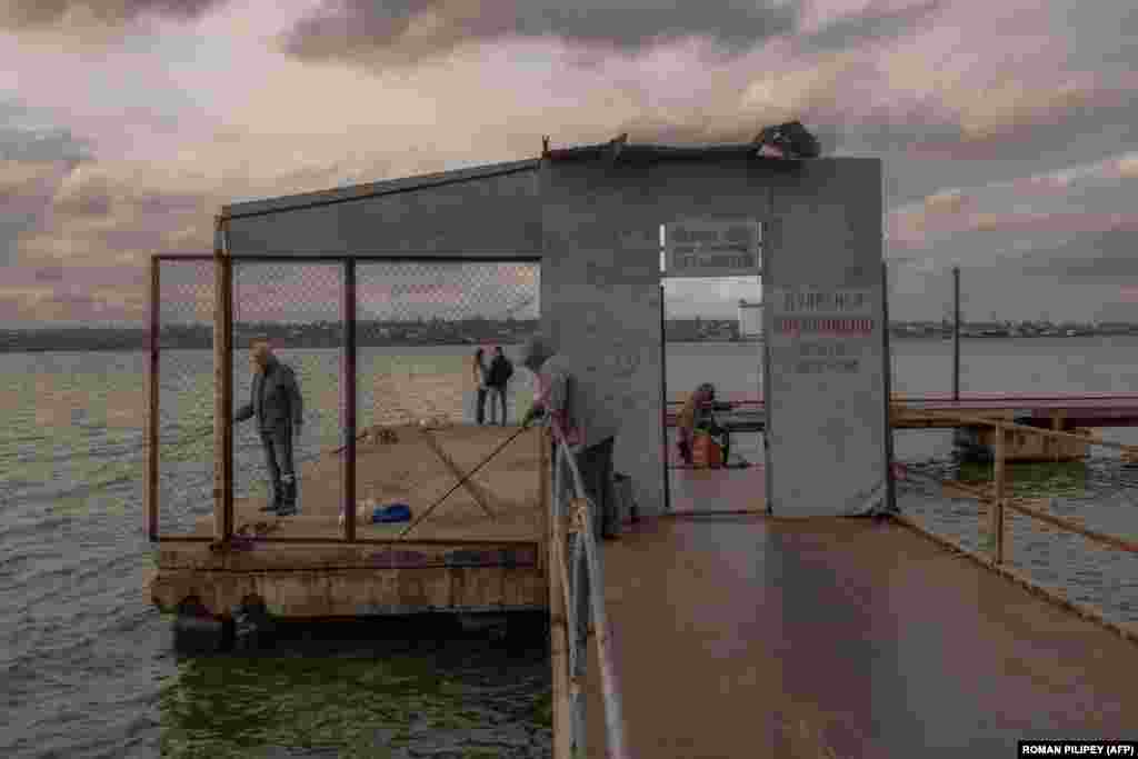 A couple stand at the end of a pier as people fish in the southern Ukrainian city of Mykolayiv.