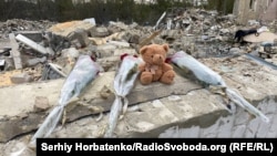 Flowers and a teddy bear are left at the site of the deadly strike in Hroza in Ukraine's Kharkiv region, which killed at least 51 people, including a child.