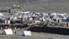 Afghan refugees sit outside their tents at a makeshift camp upon their arrival from Pakistan near the Afghanistan-Pakistan Torkham border in Nangarhar Province on November 12.