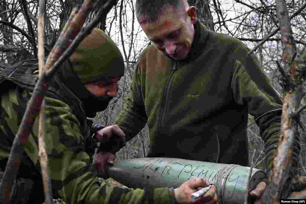 Ukrainian soldiers sign a shell &quot;for Kreminna.&quot; The eastern Ukrainian city has been fought over intensely since the early days of the 2022 Russian invasion. Several Ukrainian websites offer to write custom messages on shells destined to be fired toward Russian positions for a fee. One site claims to have raised more than $1.5 million for the Ukrainian military since launching in 2022.