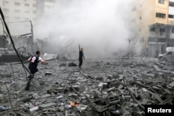 Палестинцы стоят среди обломков после ударов Израиля по жилому дому в городе Газа, 9 октября 2023 года