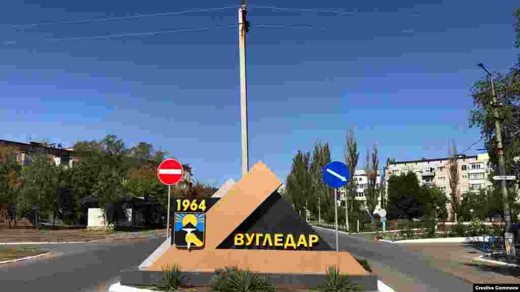 До: вітальна стела у Вугледарі Донецької області на недатованому фото до російського вторгнення. До 24 лютого 2022 року у містечку проживали приблизно 14 000 людей. Після: Вугледар з висоти пташиного польоту в лютому 2023 року. Місто було значною мірою зруйноване обстрілами, станом на січень 2024 року воно залишається під контролем України