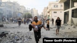 Израилдин аба соккуларынан жараат алган кызын көтөрүп бараткан киши. Газа тилкеси, 14-октябрь, 2023-жыл. 