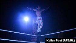  Кечистът Хентри скача от най-високото въже, с цел да се хвърли върху съперника си, който лежи на пода. 