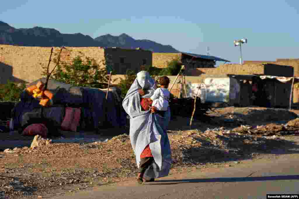 An Afghan woman holding a child walks along a road on the outskirts of Kandahar.