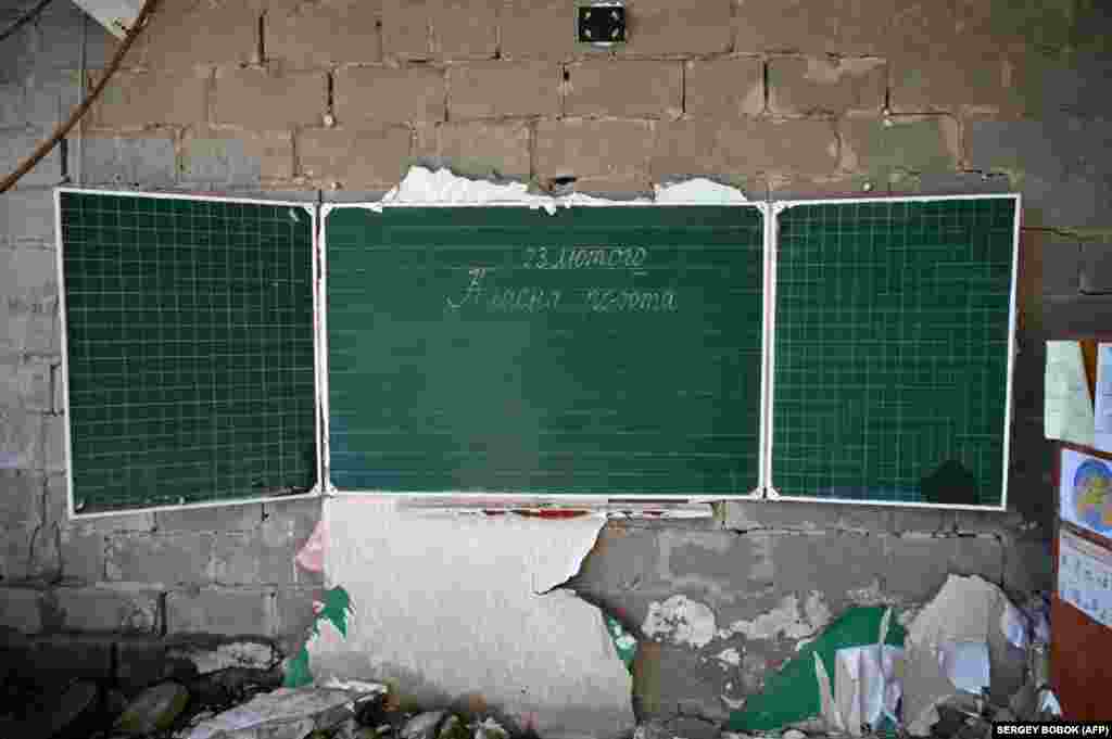 O inscripție din data de 23 februarie 2022, pe tabla unei clase din școala distrusă de bombardamente, în satul Prudeanka, din regiunea ucraineană Harkov. Fotografie realizată pe 13 martie 2023.