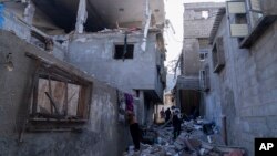 Палестинці оглядають пошкоджену будівлю після ізраїльських авіаударів по місту Хан-Юніс, Газа, неділя, 3 грудня 2023 року 