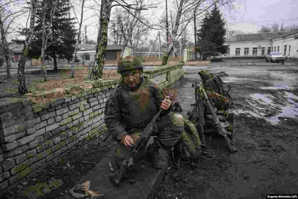 A Ukrainian soldier cleans mud from his gun after returning from the fighting in Bakhmut. &nbsp;