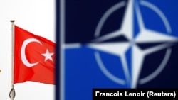 Знамето на Турција до логото на НАТО пред седиштето на Алијансата во Брисел (Илустративна фотографија)