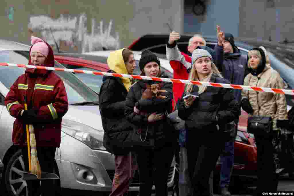 Residents stand outside of a cordoned-off area where a Russian missile struck in Kyiv.