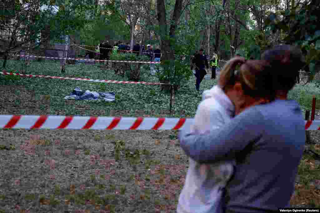 Маж утешува жена во близина на телото на лице убиено од паѓање остатоци од бомбардирањето во близина на општинската клиника. Според локалните власти, во нападот загинале најмалку три лица. Воздухопловните сили на Украина соопштија дека противвоздушната одбрана ги соборила сите 10 балистички и крстаречки ракети Искандер лансирани од руската област Брјанск во 18-тиот напад врз главниот град од почетокот на мај.