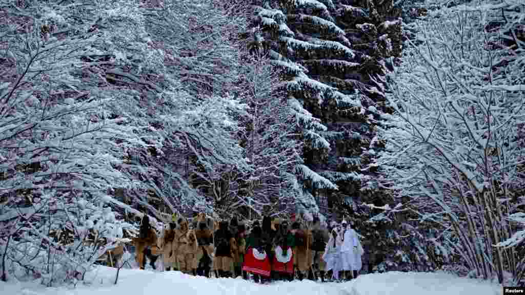 Beöltözött ünneplők állnak egy erdőben a csehországi Lidečko faluban a hagyományos, karácsony előtti parádén
