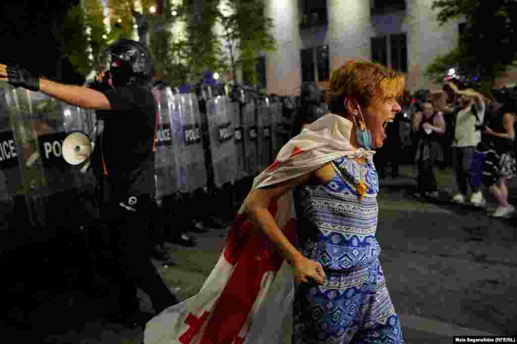 A protester draped in a Georgian flag shouts in front of a police cordon.&nbsp; The protests were a continuation of several weeks of rallies led by opposition parties and activist groups against the parliament&rsquo;s advancement of the controversial draft law, which was passed in a first reading on April 17.&nbsp; &nbsp;