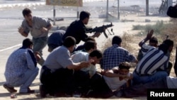 Poliția palestiniană face schimb de focuri cu soldații israelieni în timpul unor confruntări în apropierea așezării evreiești Netzreem din Fâșia Gaza, la 1 octombrie 2000.