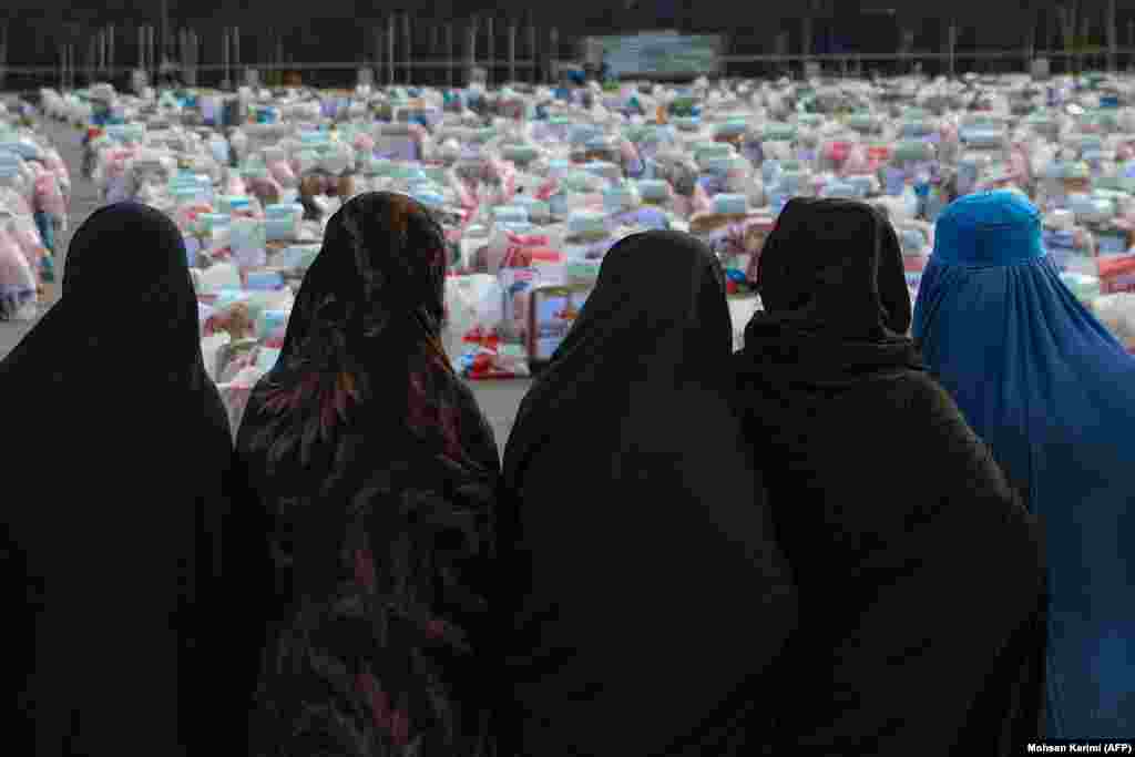  Afghan women wait to receive aid packages which includes food, clothing, and toiletries, distributed by a local charity foundation in Herat. &nbsp; 