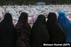 Afghan women wait to receive aid packages that include food, clothes, and sanitary materials, distributed by a local charity foundation in Herat, on January 15.