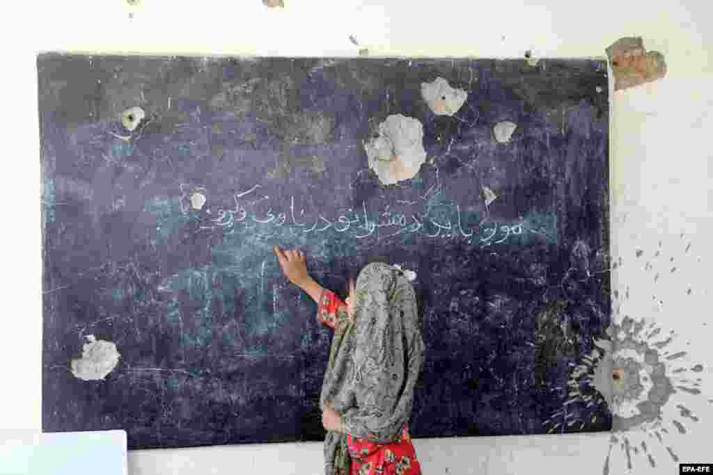 A girl attends class at a school that was damaged in conflict before the Taliban&#39;s takeover of the country in 2021 in Kandahar, Afghanistan.