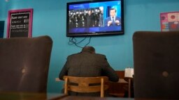 Телевизиотен екран показва китайския президент на посещение в Русия в кафене в Санкт Петербург, 20 март 2023 г.