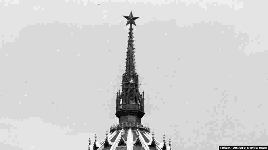 Sjajni amblem od 3 metra je imitirao crvene zvezde sovjetskog lidera Josifa Staljina koje su postavljene duž zidina moskovskog Kremlja 1937. Prema izveštaju mađarskog foto arhiva Fortepan, prvobitno je planirano da se zvezda postavi na toranj parlamenta na Staljinov 70. rođendan 1949. godine, ali je visoka logistika položaja dovela do njegovog odlaganja do 1950. godine. &nbsp;