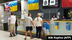 Refugees from Ukraine stop at the reception desk at an aid center in Warsaw in July 2022.