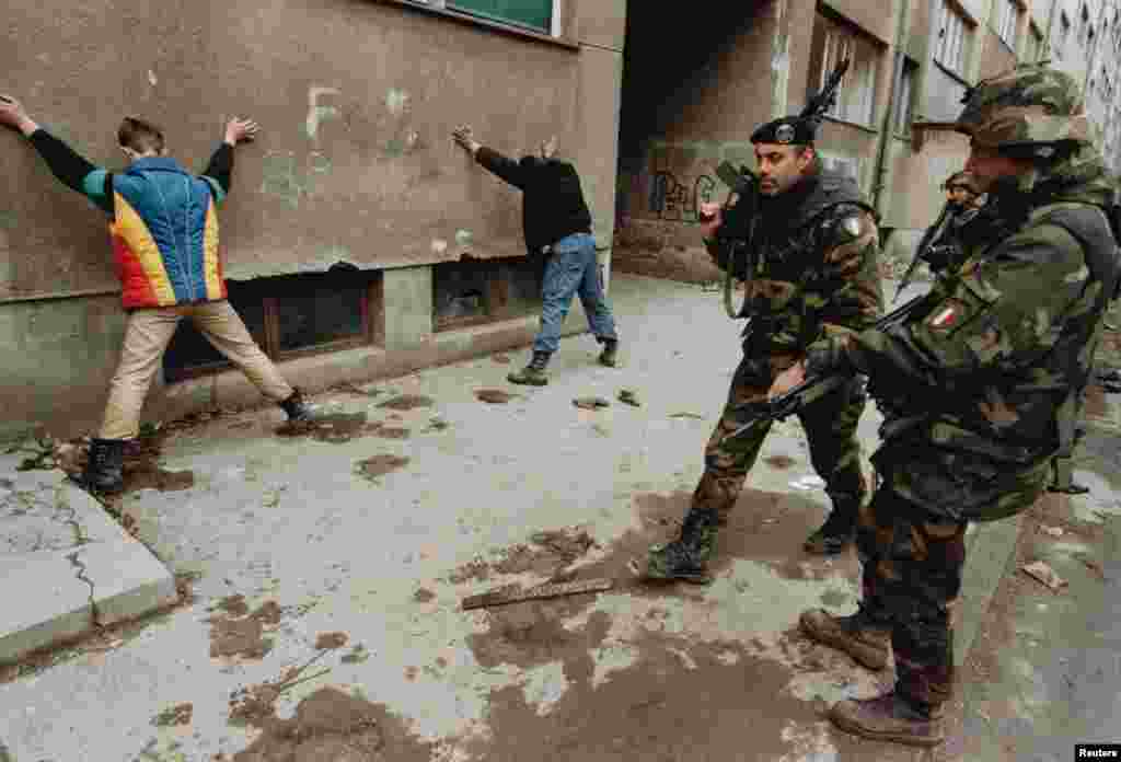 Італійські солдати і двоє підозрюваних у підпалі в Сараєво в березні 1996 року. Десятки тисяч військовослужбовців НАТО були розгорнуті для участі в конфлікті в Боснії. З того часу альянс застосував статтю 5 проти Афганістану після терористичних атак на США 11 вересня 2001 року і втрутився в громадянську війну в Лівії