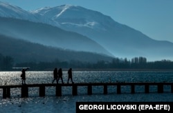 People walk over a wooden bridge at Lake Ohrid.