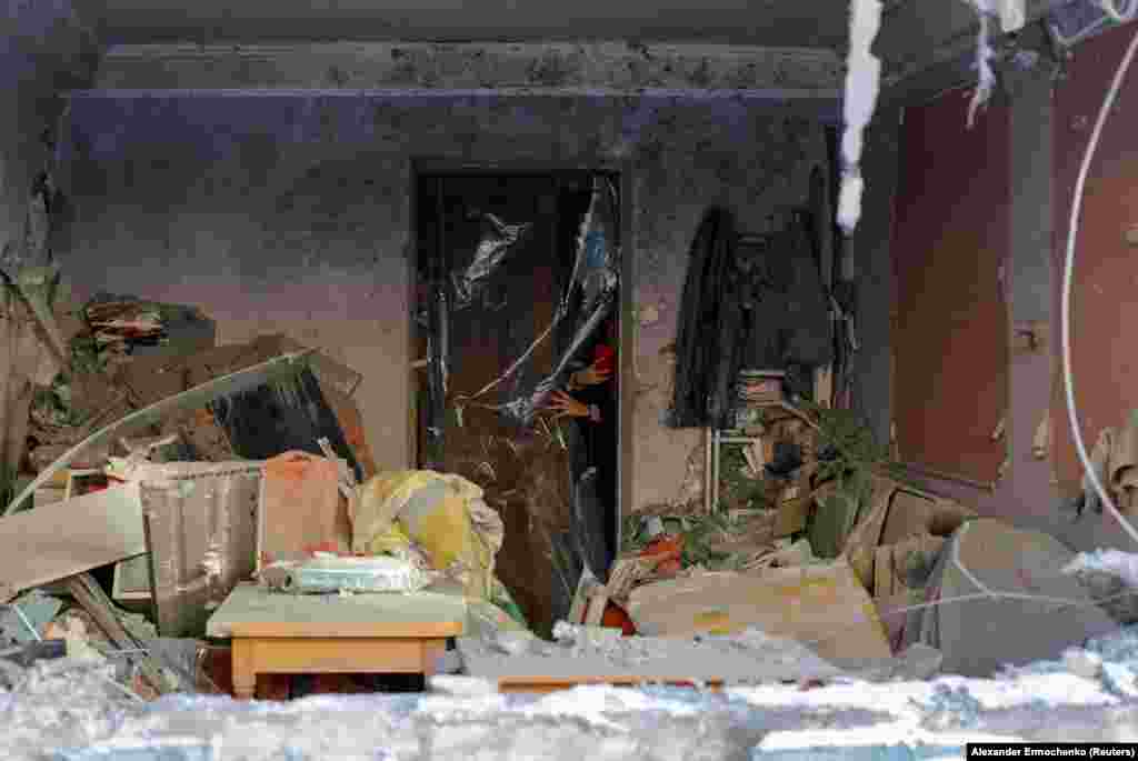 A woman takes pictures inside the apartment of her grandparents, which was damaged by recent shelling in the city of Donetsk, in Russian-controlled Ukraine.