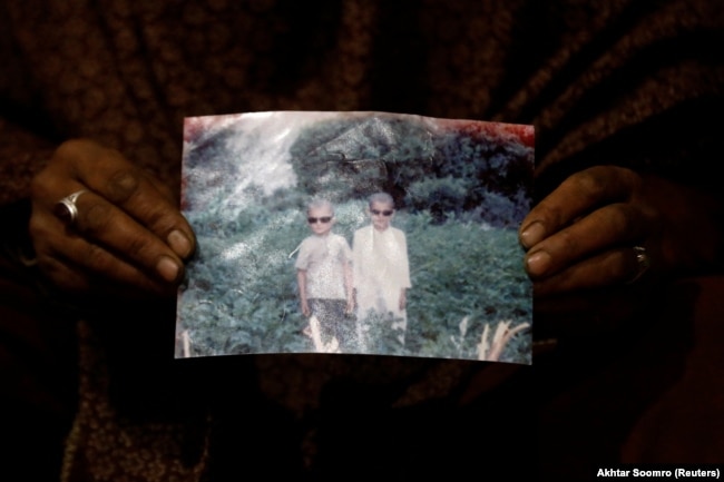 Zahra Ramzan mban një fotografi të djalit të saj 11-vjeçar, Ali Mohammad (majtas), i cili u rrëmbye nga ujërat.