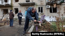 Житель Авдіївки Олександр заготовляє дрова поруч зі своїм будинком, пошкодженим російськими обстрілами, листопад 2023 року