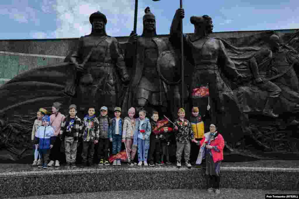 Группа детей фотографируется у монумента защитникам Отечества