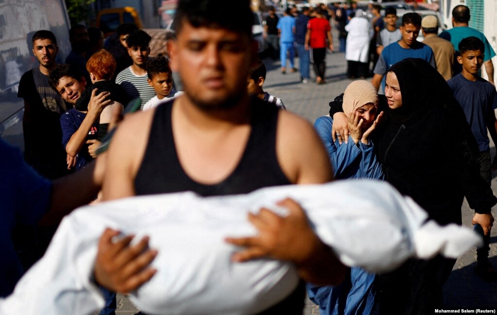Një burrë mban trupin e një fëmije palestinez të vrarë në sulmet izraelite, ndërsa prapa tij shihen njerëzit duke qarë, në Khan Younis më 17 tetor 2023.