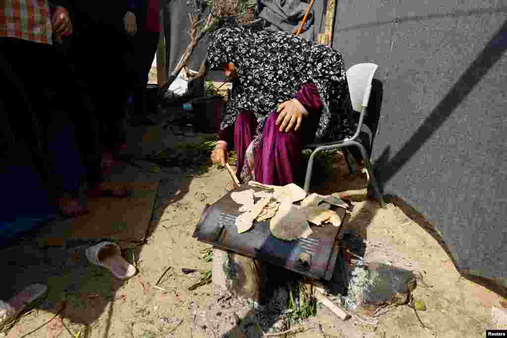 Një grua palestineze e strehuar në kamp duke pjekur petë për ushqim në një copë llamarine të improvizuar.