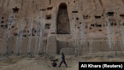 An Afghan worker pushes a wheelbarrow under the empty space where a 1,400-year-old Buddha statue once stood in Bamiyan, Afghanistan.<br />
<br />
Archaeologists working to preserve what little cultural heritage is still present in the Bamiyan Valley have been dealing with illegal excavations, encroaching developments, and Taliban gunmen who use the remnants of the Buddhas for target practice.