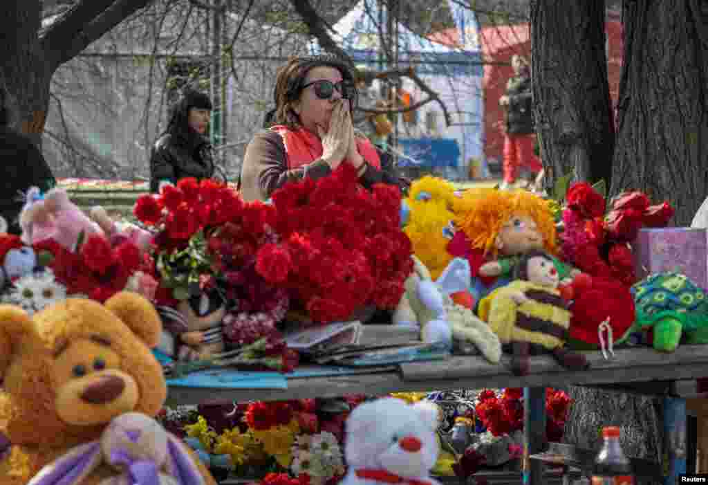  A woman visits a makeshift memorial to the victims of a drone strike that heavily damaged an apartment building in Odesa, Ukraine. &nbsp; 