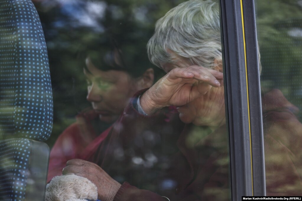 Një grua duke qarë brenda një autobusi.