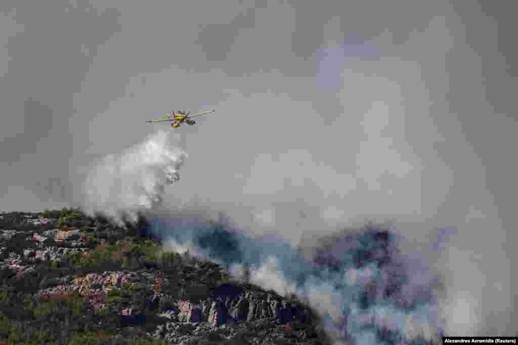 Një avion zjarrfikës shihet duke hedhur ujë në përpjekje për të shuar një zjarr në Grammatiko, pranë Athinës, Greqi, 12 gusht 2024.