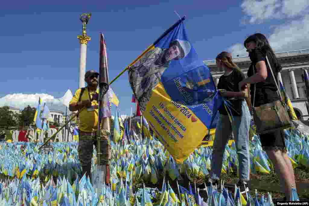 Relatives of killed Ukrainian soldier Taras Ashtema install a national flag with his portrait at a memorial for fallen Ukrainian soldiers in Independence Square in Kyiv.