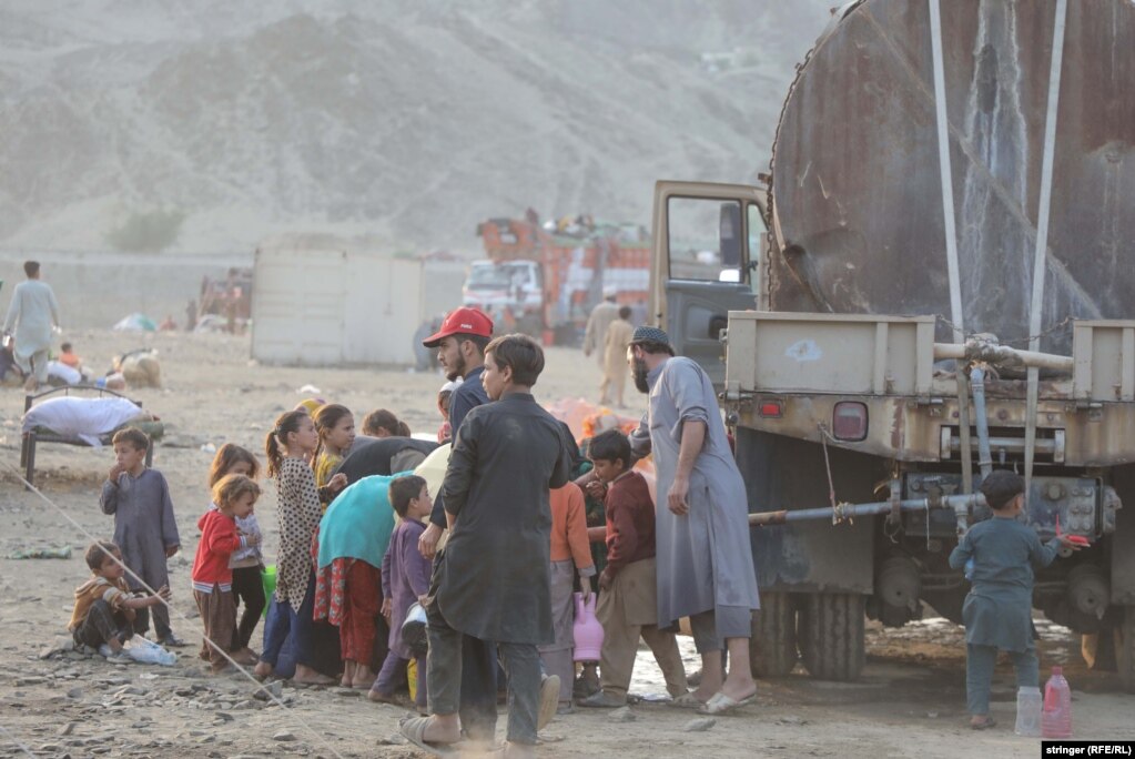  Bambini afgani raccolgono l'acqua vicino a un camion.   