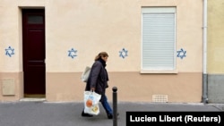 A woman walks past a building tagged with Stars of David in Paris on October 31.