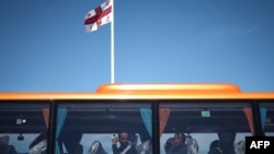 Мигранты выглядывают из окна автобуса, который отвезет их в центр приема беженцев на юго-восточном побережье Англии. 16 августа 2023 года