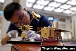 A China National Space Administration staff member assembles a model of the Chang'e 6 lunar probe ahead of a June press conference about China's lunar exploration program.