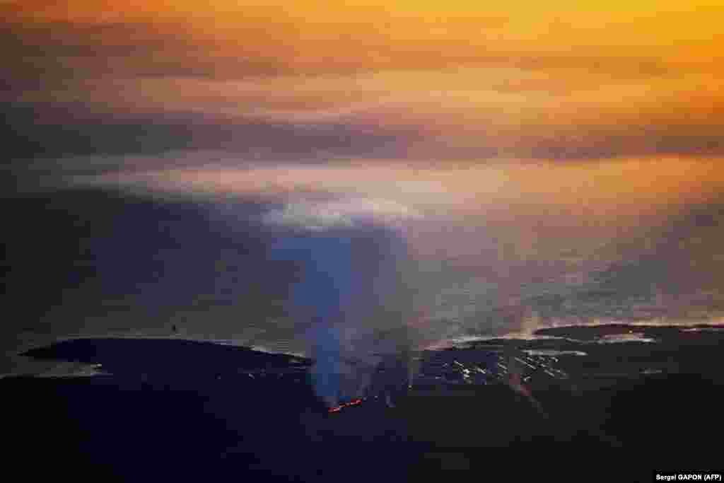 Fotografi e shkrepur nga dritarja e një aeroplani që shfaq shpërthimet the tymin e dendur afër Grindavikut.