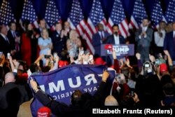 جورج سانتوس، نماینده سابق ایالات متحده، که از مجلس نمایندگان ایالات متحده اخراج شده بود، پرچمی را در حمایت از دونالد ترامپ در شب انتخابات مقدماتی نیوهمپشایر در دست گرفته است.